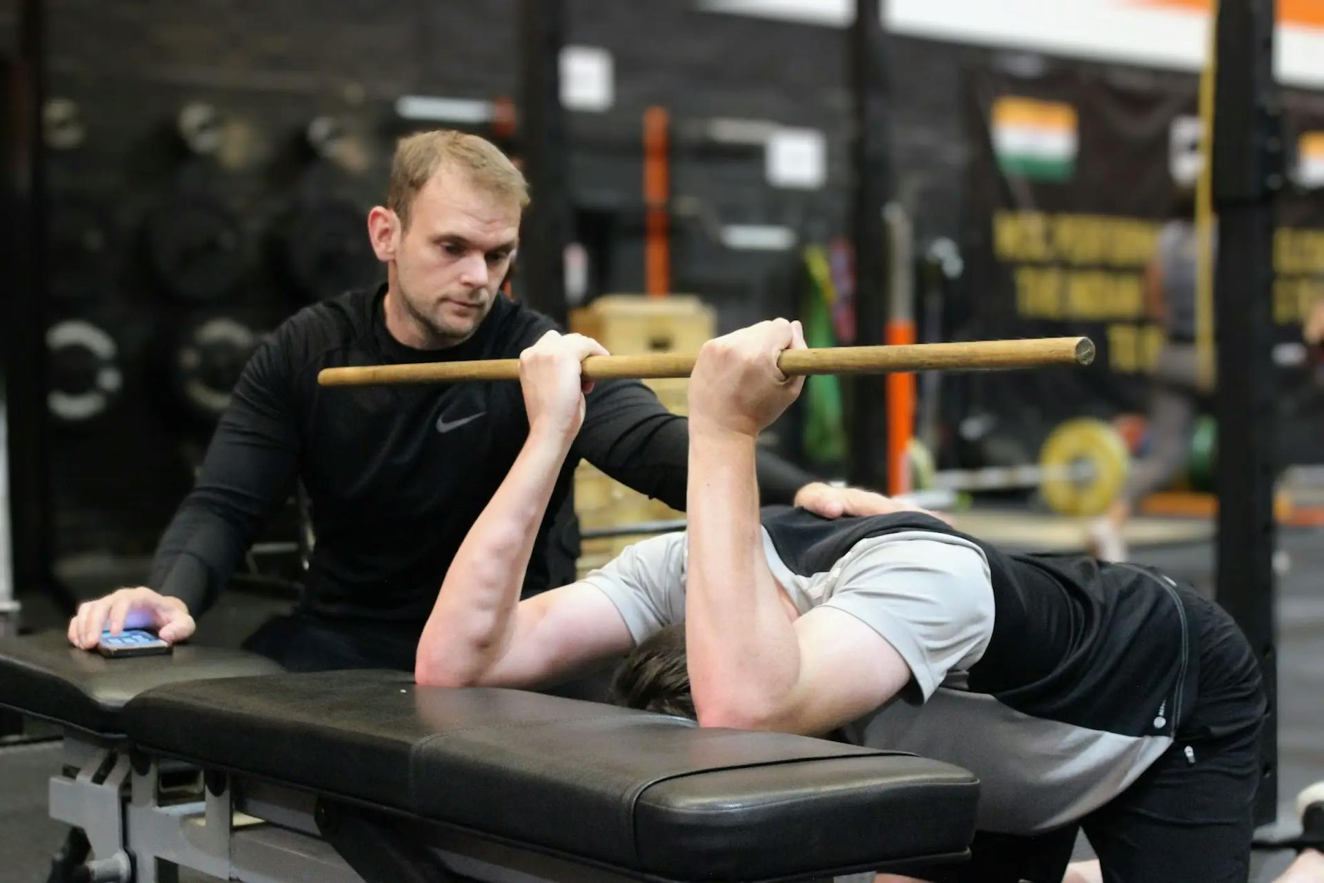 Chris watching a client perform a lat stretch on a bench