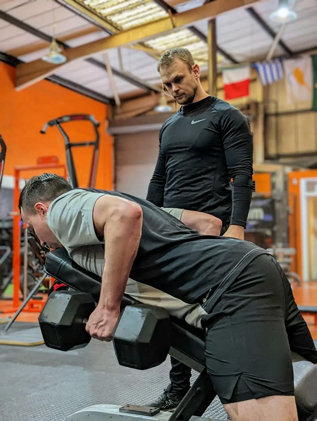 Chris watching a client perform a dumbbell row on a raised bench