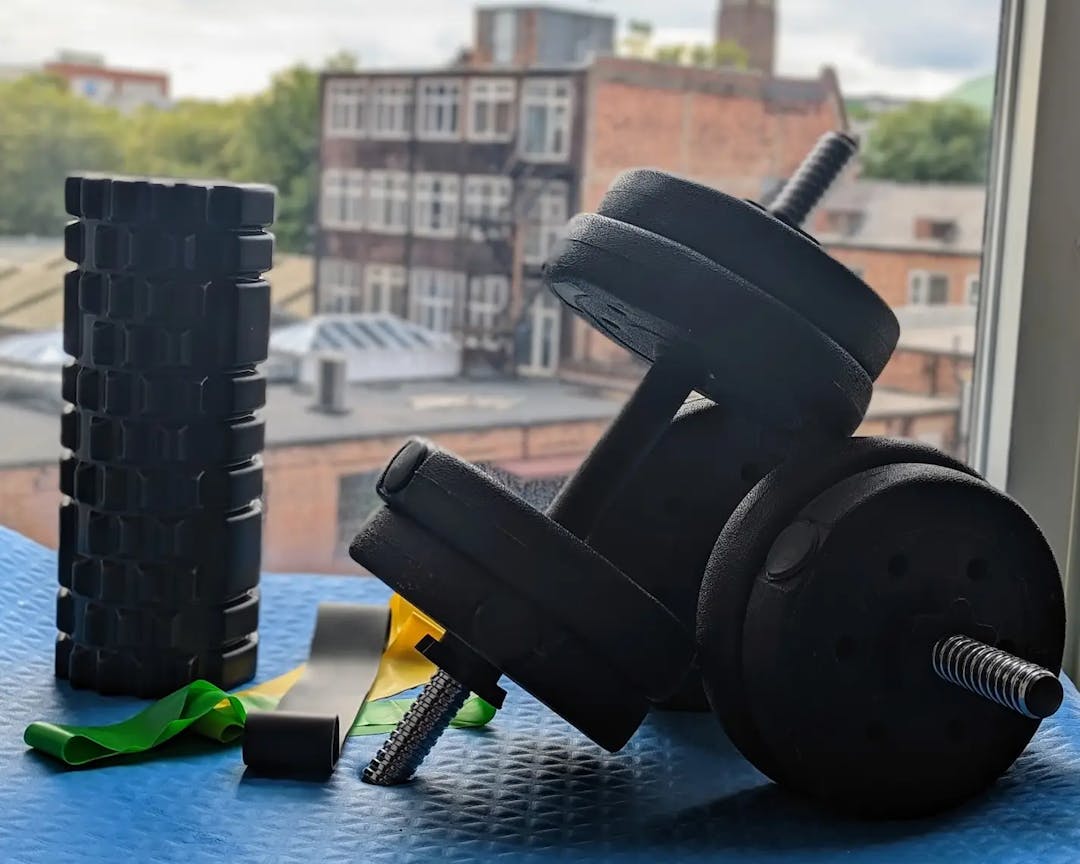 Dumbbells, resistance band and foam roller in front of a window